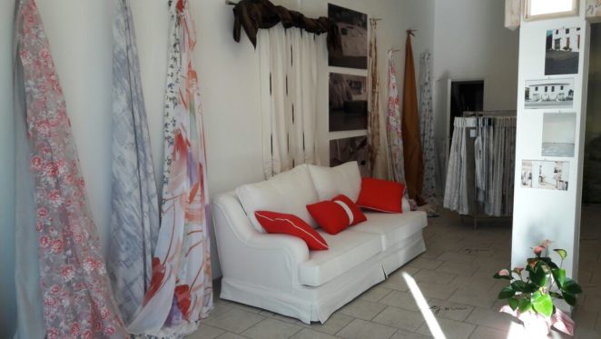 divano bianco con cuscini rossi e bianchi esposto nello showroom gani di donoratico (provincia di livorno)