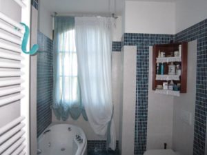 doppia tenda a pacchetto arricciato azzurro con calata in lino bianco su finestra del bagno