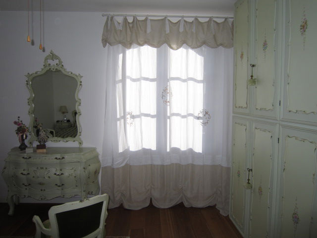 tenda classica bianca con laccetti e drappeggio in tessuto ecrù in camera stile veneziano