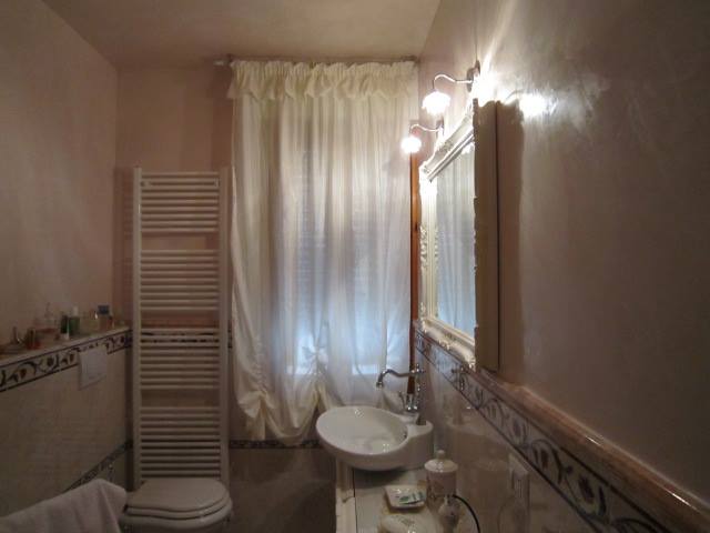 tenda in seta bianca modello a finto pacchetto su bastone in ferro battuto anticato