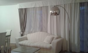 tende a pacchetto liscio bianche con calate classiche classiche per sala su binari e con mantovana bianca e fiocco fermatenda