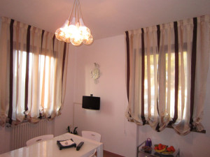 2 tende a pacchetto arricciato a righe verticali in sala da pranzo