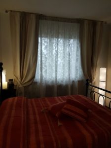 Sottotenda a motivo damascato su binario con calate ecrù su bastoni a soffitto