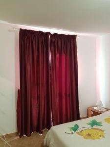 tende in raso oscurante rosso vino su binario per camera da letto