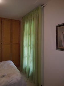 tende classiche in lino verde montate su bastone