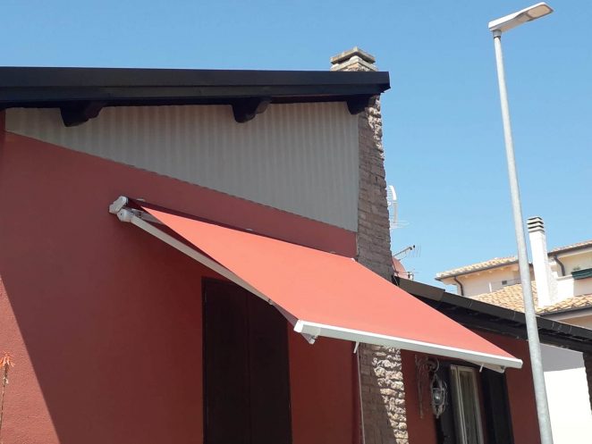 tenda a bracci su misura rossa coordinata alle mura di casa