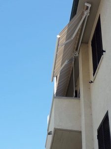 2 tende a bracci inclinate con tessuto fantasia a righe per schermatura terrazzo e finestra