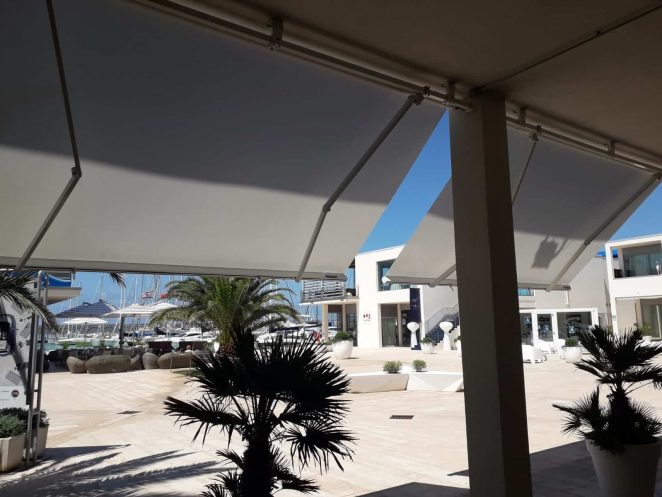 2 tende da sole a bracci estensibili motorizzate e con barra quadra in alluminio nel borgo commerciale di cala de medici