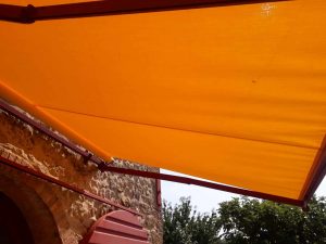 tenda a bracci a tinta unita con struttura con colore coordinato ad infissi del casolare